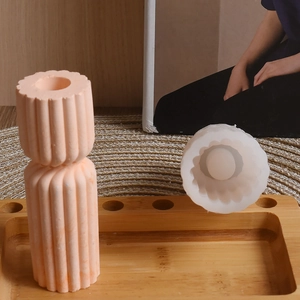 Close-up of a striped cylindrical silicone mold with a textured plaster candle holder