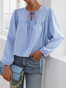 Blusa de mujer azul claro con mangas de linterna y cuello anudado en un corte holgado