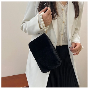 Detail of black plush square handbag featuring elegant pearl chain handle and soft texture