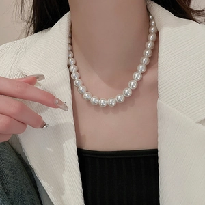 Close-up of elegant white pearl necklace on model's neck for a minimalist French style