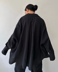 Back view of a black cotton linen shirt featuring drop shoulders and a back pleat detail