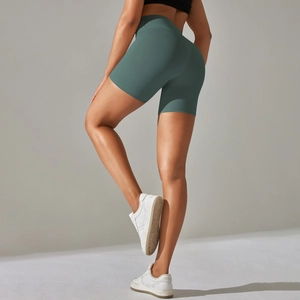 Detail view showing high-waisted dark green yoga shorts with peach hip lifting effect