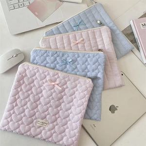 Detailed close-up of quilted laptop sleeve featuring heart patterns and soft bow detail