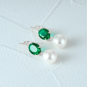 Detail of S925 silver earrings featuring faceted green gems and white pearls