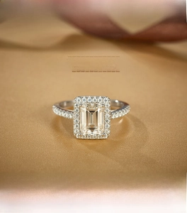 Macro shot of emerald cut moissanite ring with halo setting on a luxury silk background
