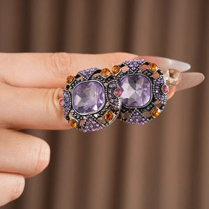 Macro shot of vintage silver earrings with square purple stone and colorful rhinestones