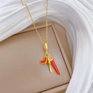 Gold titanium necklace with red heart and pepper pendants on beige jewelry box