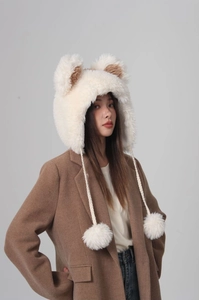 Detailed view of winter plush earflap hat featuring cute 3D bear ears and large fuzzy pom-poms