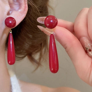 Detail of red teardrop earrings featuring a glossy lacquer finish and minimalist design