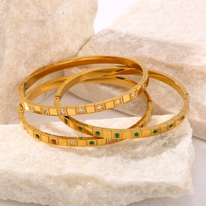 Minimalist 18K gold plated stainless steel bangles with colorful gemstones on white stone