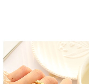 Close-up of golden layered fox open ring worn on finger with elegant ceramic background