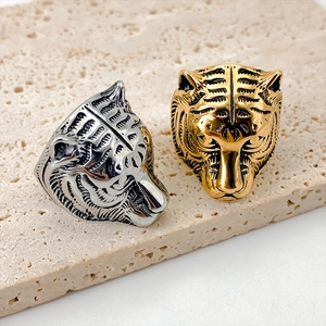 Close-up of gold and silver tiger head rings on a textured stone surface