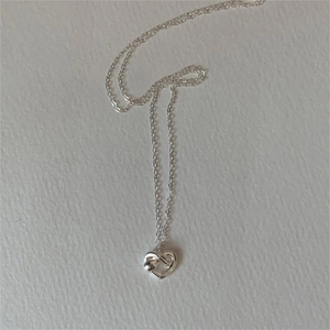 Macro shot of 925 sterling silver heart knot necklace pendant with delicate cable chain
