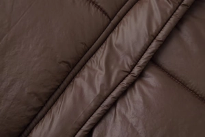 Gros plan du tissu matelassé marron foncé avec une finition lisse et brillante