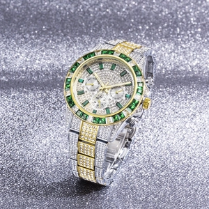 Close-up of gold-silver luxury watch with emerald crystals and full diamond encrusting
