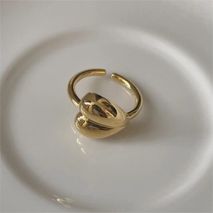 Detailed view of an adjustable golden heart-shaped sterling silver ring on white ceramic