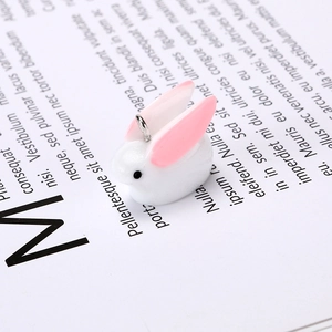 Close-up of a white resin rabbit charm with pink ears and a silver metal hanging loop