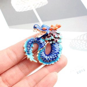 Macro detail of a blue enamel dragon brooch with golden scales and orange accents