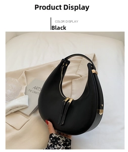 Detail of black matte faux leather crescent bag with gold zipper and stylish hardware