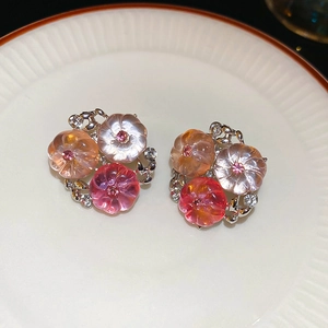 Macro shot of silver flower stud earrings with peach resin petals and crystal accents