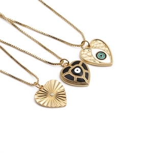 Trois colliers cœur dorés avec motifs mauvais œil et émail noir sur fond blanc pur