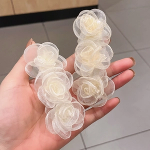 Detail shot of two cream mesh camellia flower hair clips with delicate petal textures