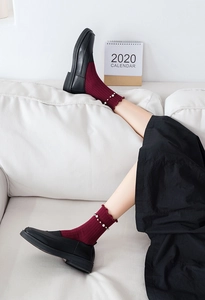 Detail of burgundy crew socks featuring elegant white pearls and ruffled lace trim
