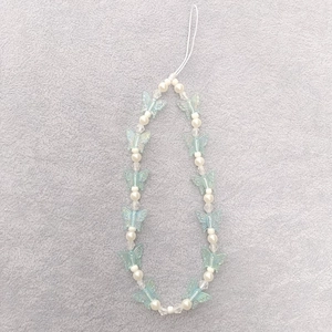 Close-up of blue butterfly acrylic beads and white pearls on a mobile phone strap