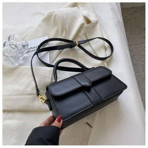 Detail of black PU leather crossbody bag with golden hardware on a white background