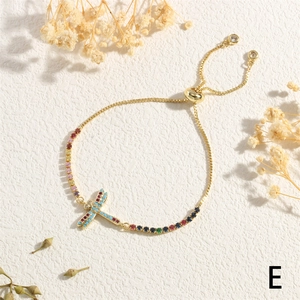 Detail of adjustable gold bracelet with colorful zircon dragonfly charm and dark beads
