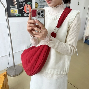 Red nylon dumpling crossbody bag with adjustable strap worn by model in casual style