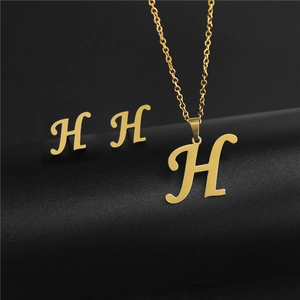 Close-up of golden stainless steel H-letter pendant necklace and stud earrings set