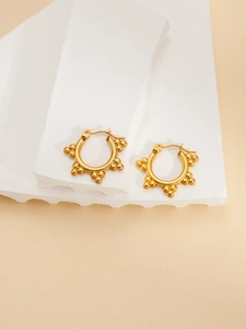 Detailed shot of gold-plated hoop earrings with beaded clusters on white stone