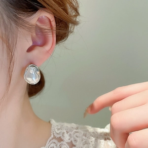 Close-up of irregular baroque pearl earring with silver trim on a model's ear