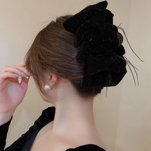 Detail of elegant black velvet hair claw clip with feathers and sequins for updos
