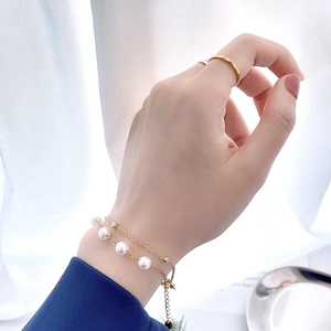 Détail du bracelet en titane doré avec perles blanches et design de chaîne à double couche