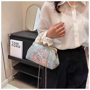 Detail of light blue embroidered handbag with pink floral patterns and gold chain strap