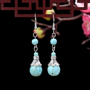 Detail of ethnic style turquoise flower earrings with silver accents on a dark background