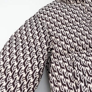 Detailed close-up of beige quilted jacket sleeve featuring brown geometric pattern print