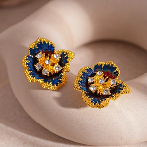 Détail macro de boucles d'oreilles fleurs rétro avec émail bleu et centre en cristal