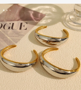 Detail view of bold two-tone gold and silver open bangles with high-polish finish