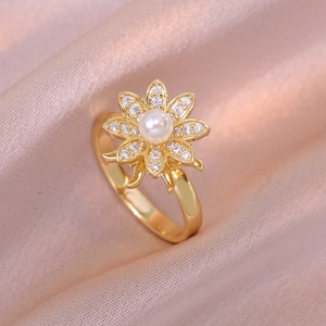 Elegant gold flower ring with center pearl and zircon petals on soft silk background