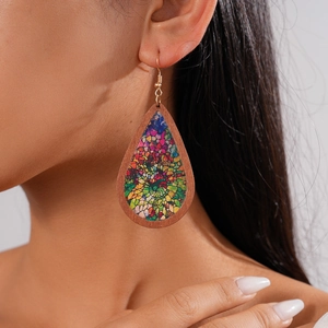 Macro detail of teardrop wooden earrings with colorful mosaic patterns on model