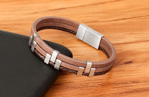 Detailed macro view of men's triple-layer brown leather bracelet with brushed metal accents