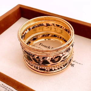 Detail of layered gold bracelets with leopard print pattern and sparkling rhinestones
