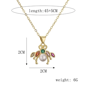 Detail view of insect pendant necklace with colorful gemstones and white pearl on a gold chain