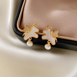 Macro de boucles d'oreilles licorne dorées avec nacre et perles sur soie champagne