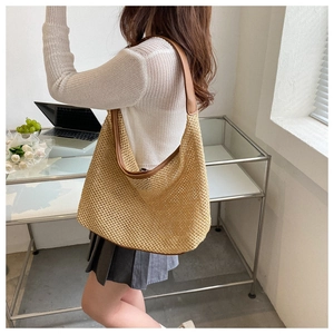 Detail of khaki woven straw tote bag with brown PU leather shoulder strap and texture