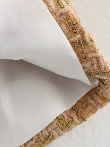 Macro shot of pink tweed fabric with gold threads and white lining craftsmanship