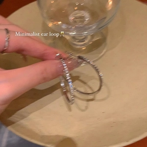 Close-up of sparkling silver hoop earrings with inset crystals held by hand